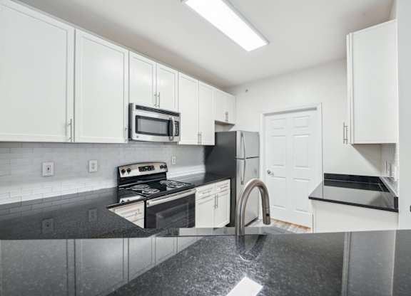 A kitchen with black countertops and white cabinets.
