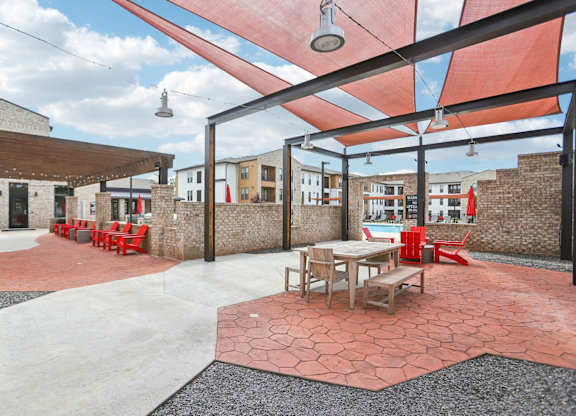 A patio with tables and chairs under a red awning.
