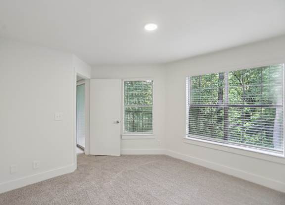 A bedroom with a carpeted floor and a window with blinds.