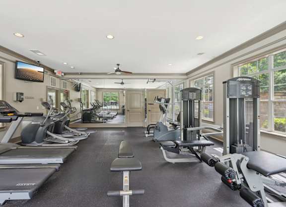 A spacious gym with a variety of equipment including treadmills, elliptical machines, and weight machines.