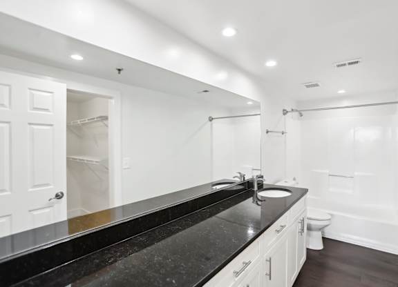 A bathroom with a black countertop and white walls.