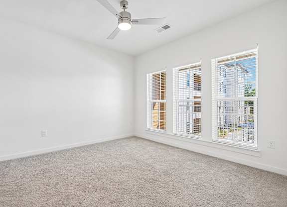 A room with a ceiling fan and carpeted floor.