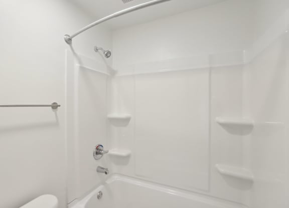 A white bathroom with a toilet, tub, and shower.