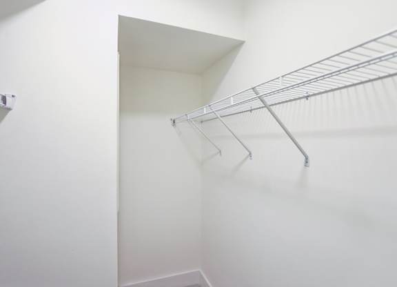 A white closet with a metal racks.