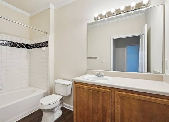 A bathroom with a white toilet, sink, and shower tub