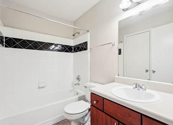 bathroom with brown cabinets and white sink and shower tub