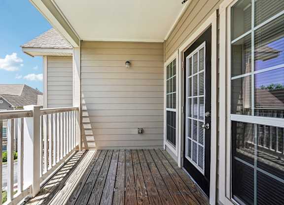 A balcony with a black door and a white railing.