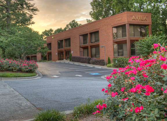 A building with the name AVILA on it is surrounded by flowers and trees.