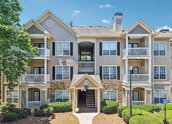 A large two-story apartment building with a stone facade and multiple balconies.