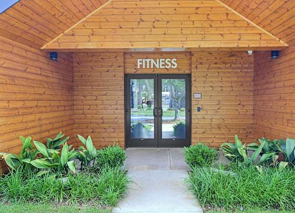 A fitness center entrance with a glass door and a sign above it.