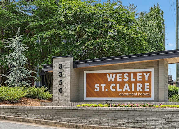 The sign for Wesley St. Claire Apartment Homes is displayed in front of a building.