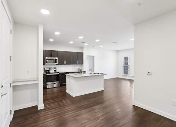 A kitchen with dark brown cabinets, stainless steel appliances and granite countertops