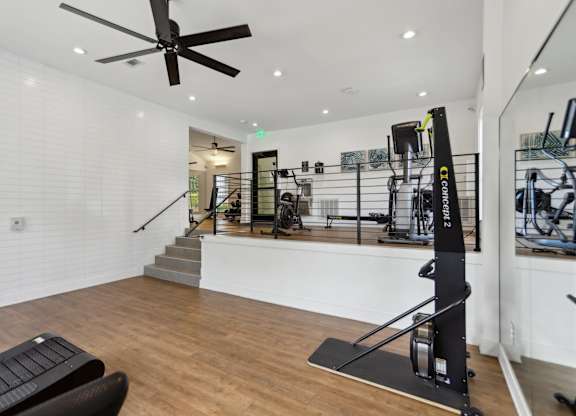 A gym with a variety of equipment including a squat rack and a bench.
