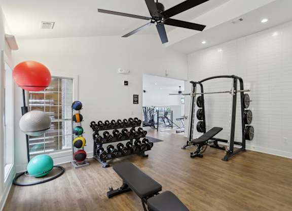 A gym with a variety of equipment including weights and exercise balls.