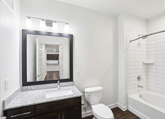 A bathroom with a white tub and shower, sink, and toilet.