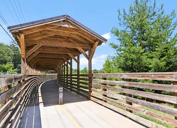 A covered wooden bridge with railing that leads to the Beltline and Bobby Jones Golf Course.