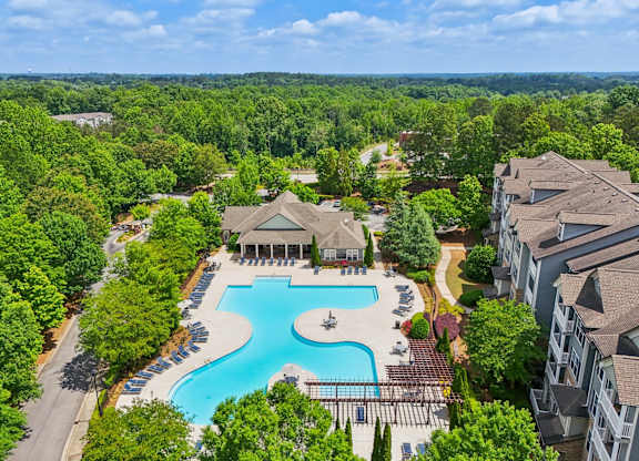 A large swimming pool surrounded by trees and resident clubhouse