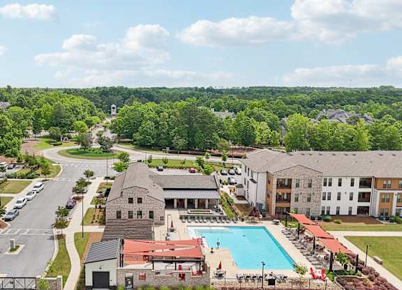 A large apartment complex with a swimming pool in the middle and many covered lounge areas