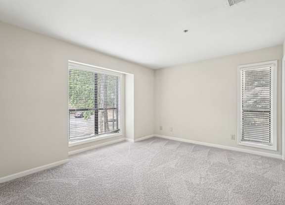 A large bedroom with a carpeted floor and windows
