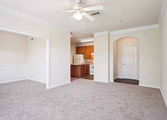 A spacious  living room with a ceiling fan and carpeted floor.