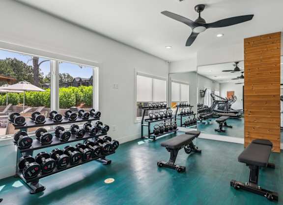 A gym with a row of dumbbells on the left and a mirrored wall on the right.