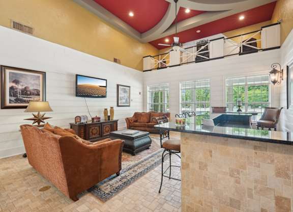 Resident clubhouse with a TV, couch, bar are with stools and a coffee machine station.