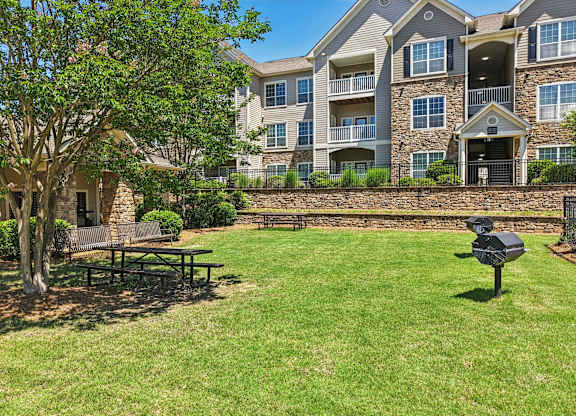 A large grassy area with grills, picnic tables, and benches