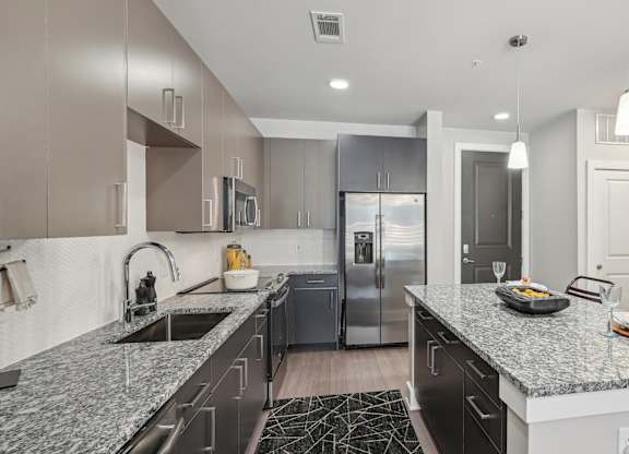 A modern kitchen with a granite countertop and stainless steel appliances.