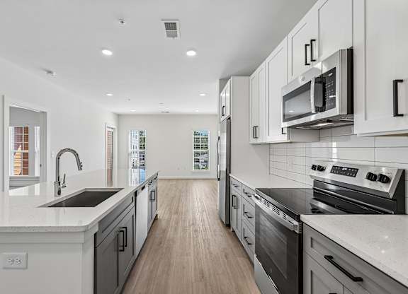 A modern kitchen with white cabinets and stainless steel appliances.