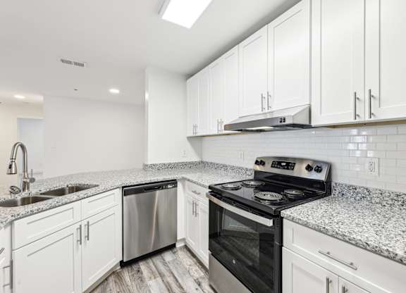 A kitchen with stainless steel appliances, white cabinets and a granite countertop.