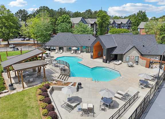 A large outdoor swimming pool surrounded by lounge chairs and umbrellas.