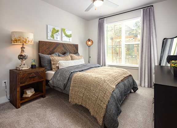 A spacious bedroom with a bed, nightstand, and window.
