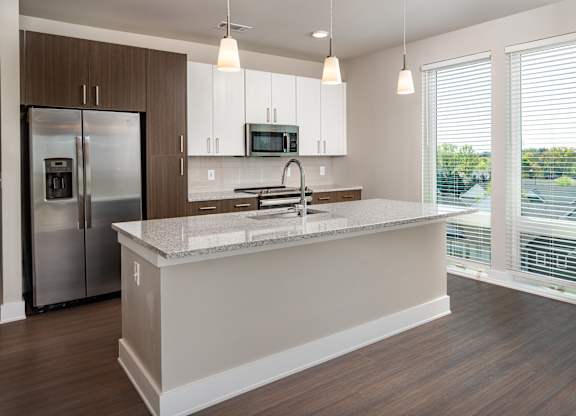 A modern kitchen with a stainless steel appliances and floor to ceiling windows