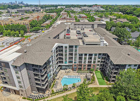 An aerial view of 915 Glenwood apartments with a swimming pool, green area with walking path,  and a parking lot.