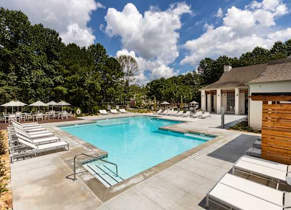 A large swimming pool surrounded by sun loungers and umbrellas.