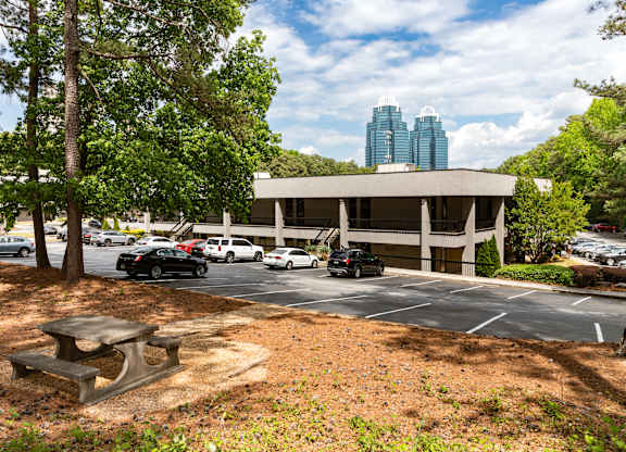 A parking lot with cars and a picnic table in front of a building. office space sandy springs, brookhaven, perimeter,  buckhead