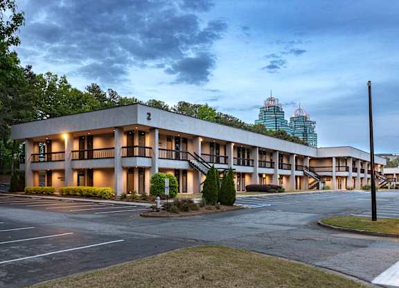 A large building with a parking lot in front of it. office spaces in sandy springs, brookhaven, and buckhead