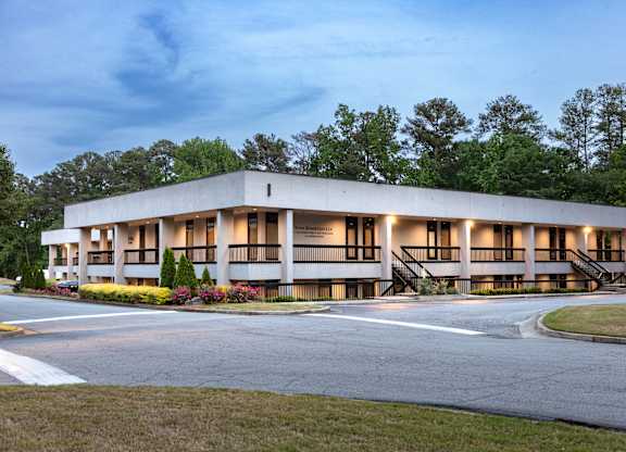 A modern building with a curved facade and a landscaped front yard.