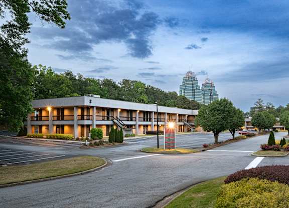 A large building with a parking lot in front of it. office spaces in sandy springs, brookhaven, and buckhead