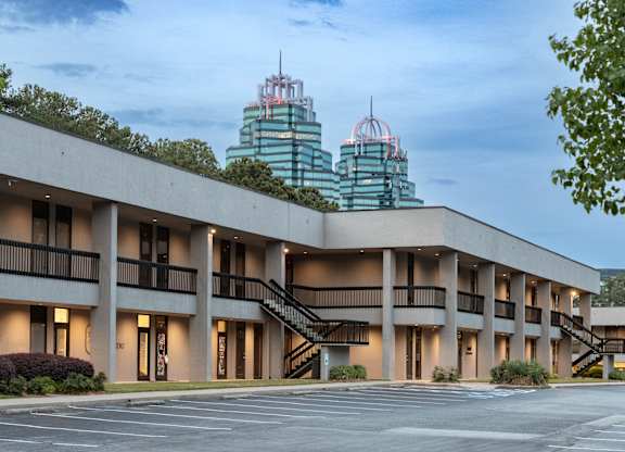 A large building with a parking lot in front of it. office spaces in sandy springs, brookhaven, and buckhead