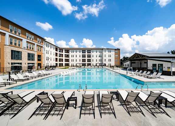 A large swimming pool surrounded by sun loungers and chairs.