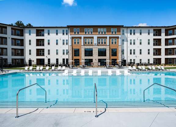 A large swimming pool in front of a multi-story apartment building.