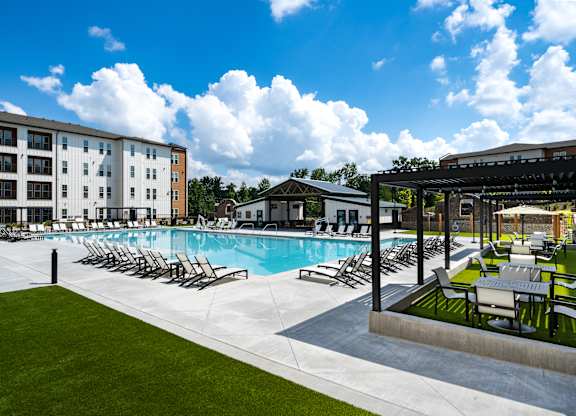 A large swimming pool surrounded by lounge chairs and umbrellas.