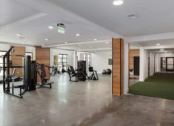 A gym with a variety of equipment including treadmills, weights, and exercise machines.