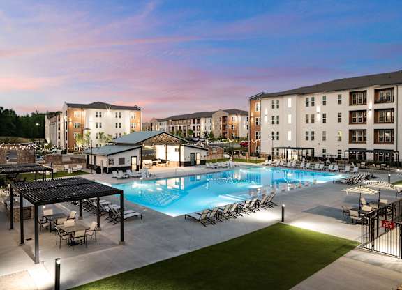 A large swimming pool surrounded by a grassy area and a few chairs.