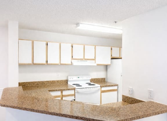 A kitchen with white appliances and a granite countertop.