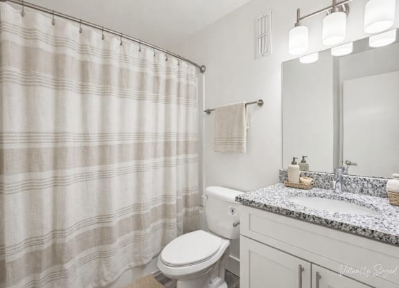 A bathroom with a toilet, sink, and shower curtain.