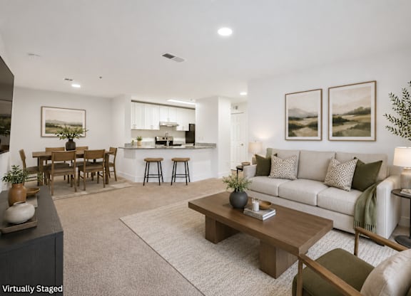 A modern living room with a white couch, wooden coffee table, and a dining table with chairs.