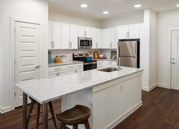 A large kitchen with a granite countertop and stainless steel appliances. with white cabinets
