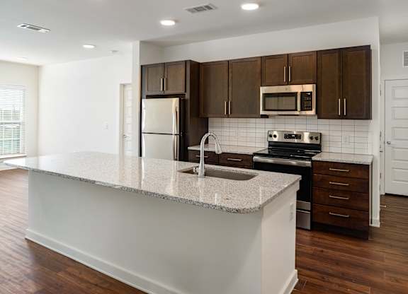 A large kitchen with granite counter top and brown cabinets.